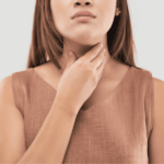 Woman in a sleeveless top touches her throat, suggesting discomfort—similar to symptoms discussed in Research Verified® Thyroid Aid Reviews—against a plain background.