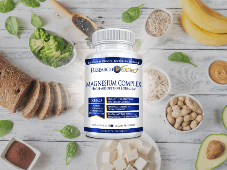 Your Complete Guide to Magnesium: Benefits, Types, and Our Unique Formula A bottle of Research Verified Magnesium Complex supplement, featuring multiple magnesium types, sits among spinach, bananas, nuts, tofu, avocado, and whole grain bread on a wooden table.