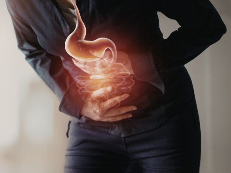Person clutching their stomach in pain, with a glowing illustration of the stomach and intestines overlayed, indicating abdominal discomfort or digestive issues.